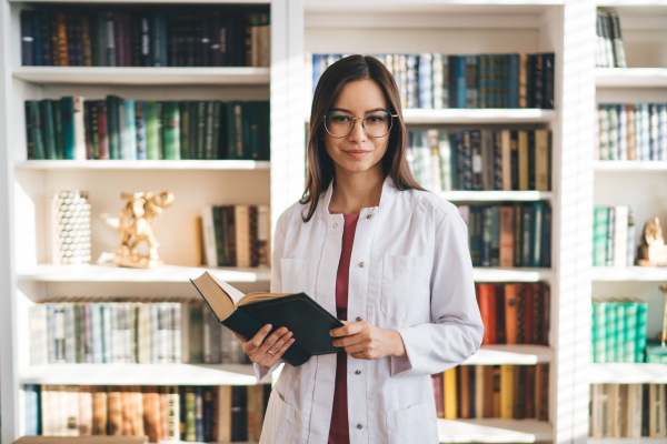 Doctor holding book with bookshelf in background