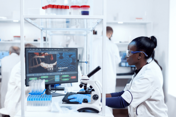 Biotechnologist doing research on computer while microscope is in front of her. With a skills shortage in Canada, you can find biotechnology career opportunities in biosciences, health, genomics, and other areas.