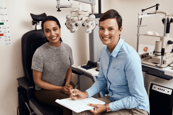Optometrist and patient smiling at camera