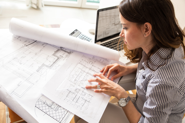 An experienced female architect is reviewing drawings. An architect's salary can increase based on level of experience, type of work they do, and location. 