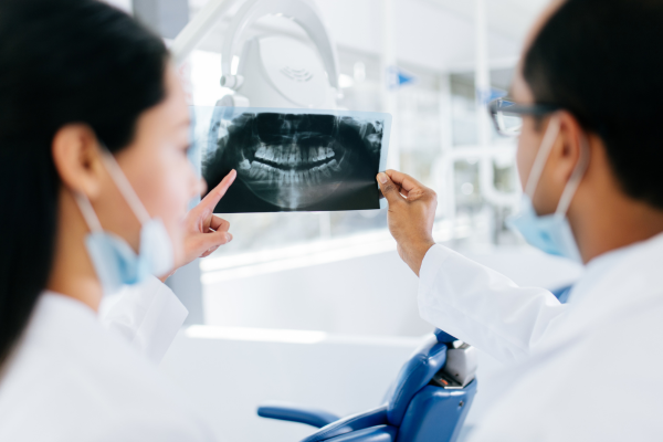 Two dentists are examining an x-ray before proceeding with a procedure. Dentist salaries in Canada are lucrative, especially for experienced dentists.