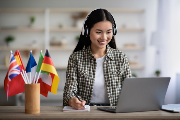 An employment counsellor wearing headphones is connecting online with a prospective newcomer to Canada to discuss pre-arrival employment services.