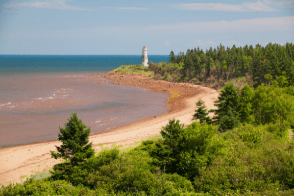 Atlantic Beach Coast in New Brunswick, Canada with a lighthouse in the background.