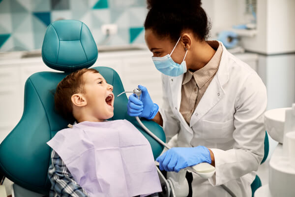 Happy dental hygienist doing a cleaning on boy