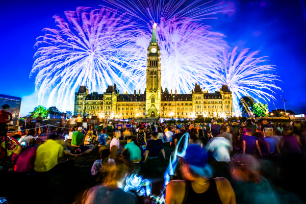 A large crowd is gathered to watch the Canada Day fireworks display on Parliament Hill in Ottawa. Canada Day 2023 will celebrate the country's 156th birthday.