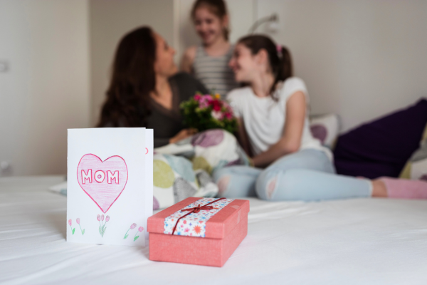 Two young daughters giving their mom a card and gift for Mother's Day. 