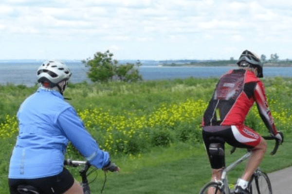 Two cyclists along the Waterfront Trail in the fall with Lake Ontario in the background.