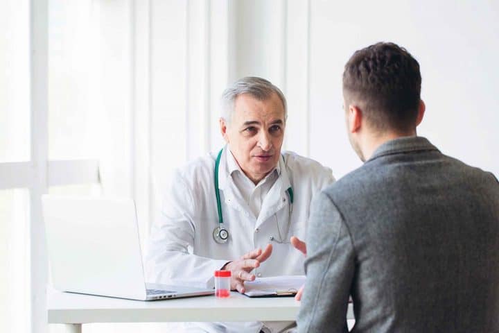 A male doctor discussing health care with a male patient. 