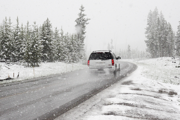 A car driving on a snow covered road in winter. Installing winter tires is a good winter driving tip to increase safety.