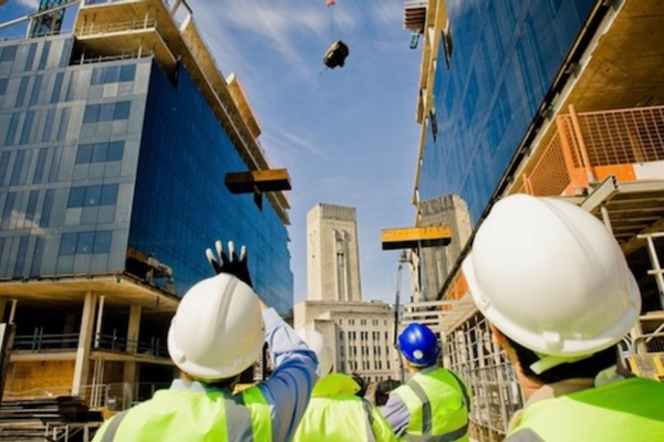 Construction employment is a growing sector in Canada. Employees on a construction site wearing hardhats and looking up at a crane.
