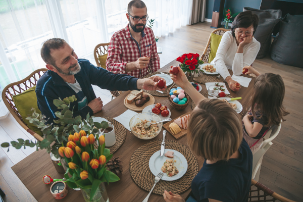 A family is eating breakfast at a dining table decorated with colourful eggs and and tulips to celebrate Easter in Canada.