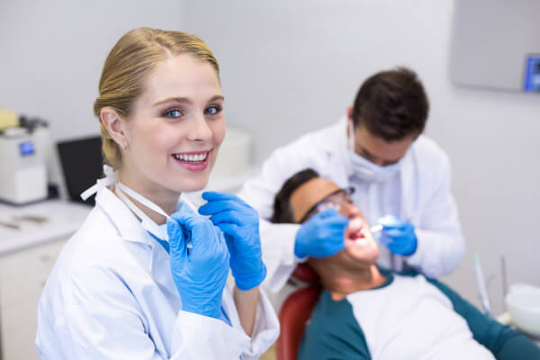 Dental hygienist smiling, while dentist works on patient