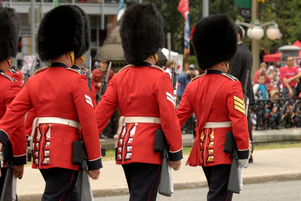 Members of the Ceremonial Guard march in a Canada Day parade in Ottawa, Ontario. The guards are dressed in their distinctive scarlet tunics and bearskin caps. 