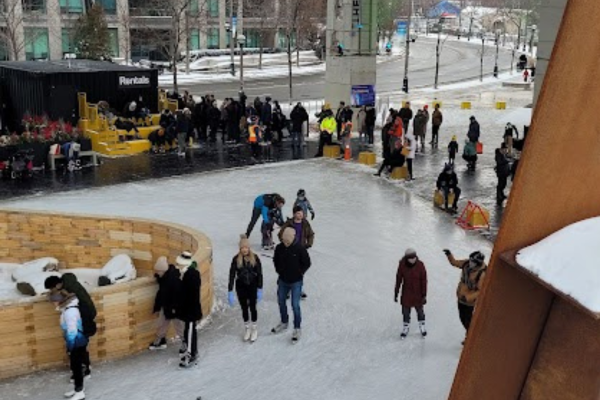 Adults and children are skating outdoors on The Bentway ice rink during the Family Day statutory holiday.