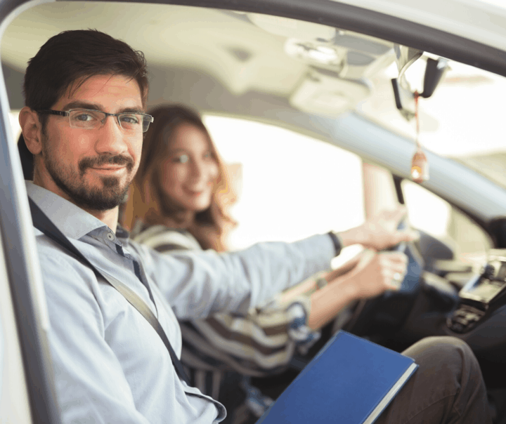 A male driving instructor in seated in the passenger seat and a female is seated in the driver's seat while she is learning to drive a car in Canada.