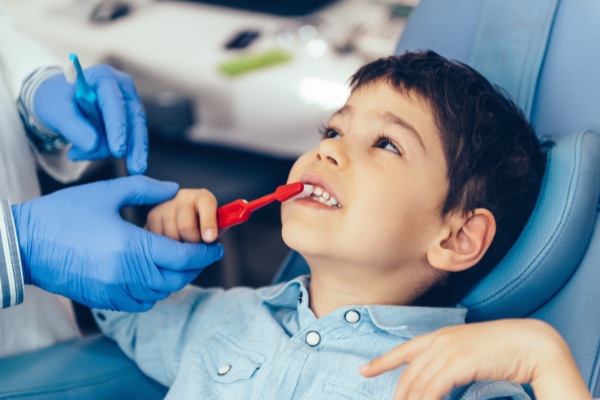 A dental hygienist teaching a young boy about dental hygiene and teeth brushing