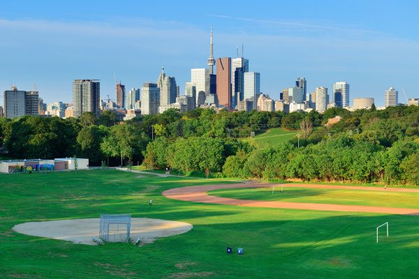 A neighbourhood park is set against the Toronto skyline. Real estate agents can let you know about neighbourhoods that will best suit your needs.