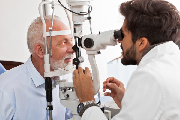 An eye doctor is examining an older male patient to assess vision needs. Optometry is a high demand career given Canada's ageing population and age-related eye conditions.
