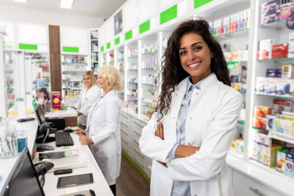 Pharmacist smiling at camera and standing in pharmacy