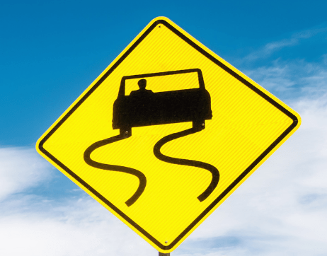 Yellow and black road sign that shows a car with skid marks to indicate the road is slippery. Follow winter driving tips to help you when you hit black ice. 