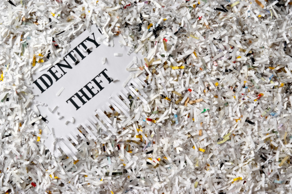 Shredded paper is placed over a large piece of paper with the words identity theft. Shredding documents that include your social insurance number can protect you against fraud.