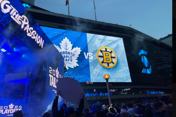 A crowd is looking up at a big screen outside of the Scotiabank arena to watch the Stanley Cup playoff game between the Toronto Maple Leafs and Boston Bruins.
