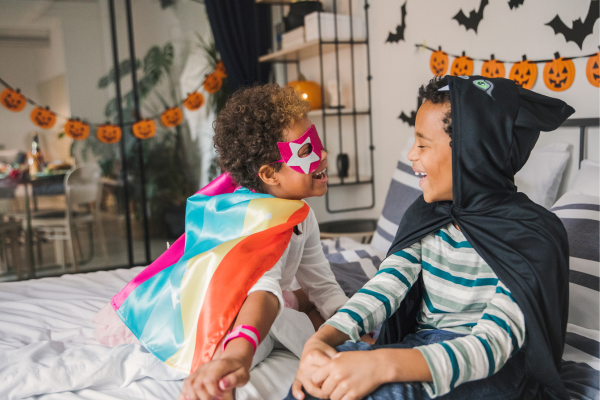 Two young children wearing costumes and getting ready to go trick-or-treating on Halloween