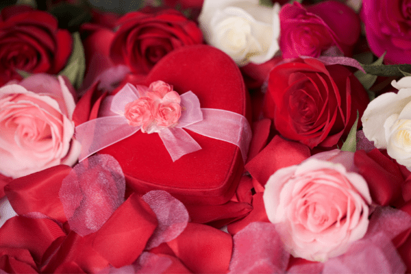 A box of Valentine's Day chocolate is placed among pink and red roses