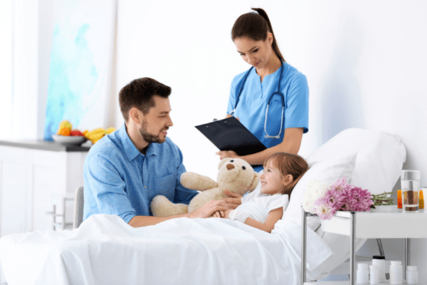 A young girl laying in a hospital bed with her father and a nurse at her side. Apply for your Ontario health card to ensure your hospital visits are covered. 