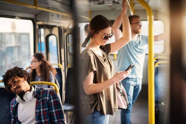 A woman is looking at her mobile phone while riding public transit in Hamilton. 