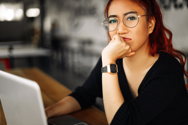 Young woman wearing glasses is thinking while she completes a personality assessment on her computer. Self awareness is key to career success. 