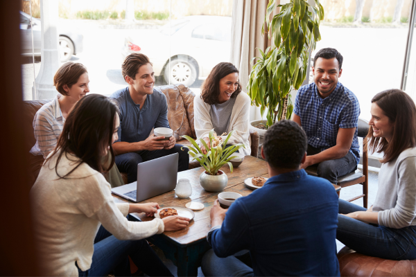 A group of people are seated together and drinking coffee. Settlement services can help you meet other newcomers and build personal and professional relationships. 