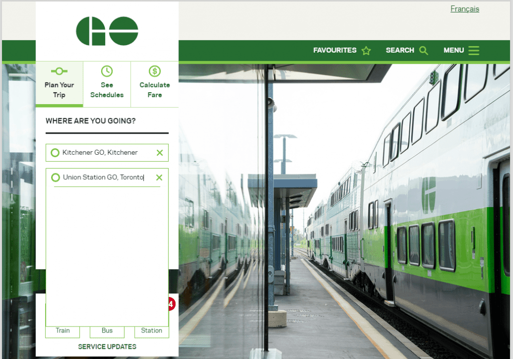 A GO train and platform showing a schedule from Kitchener-Waterloo to Toronto.