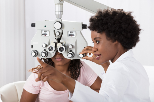 Optometrist conducting an eye exam with a female patient. Optometrist job requirements include examining, diagnosing, and treating eye conditions.